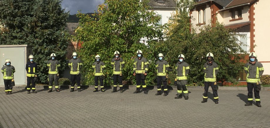 Elf Feuerwehrangehörige im Gruppenbild mit Abstand